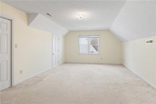 bonus room featuring a textured ceiling, light carpet, and lofted ceiling