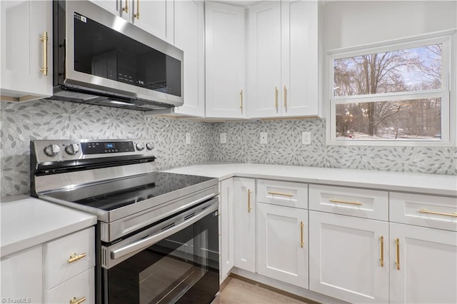 kitchen featuring light wood finished floors, stainless steel appliances, light countertops, decorative backsplash, and white cabinets