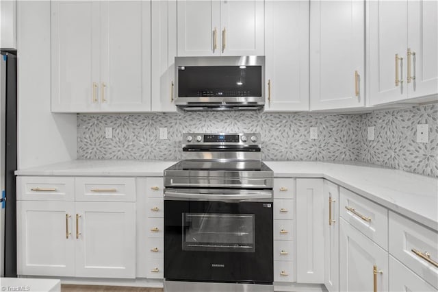 kitchen featuring light stone countertops, white cabinetry, stainless steel appliances, and backsplash