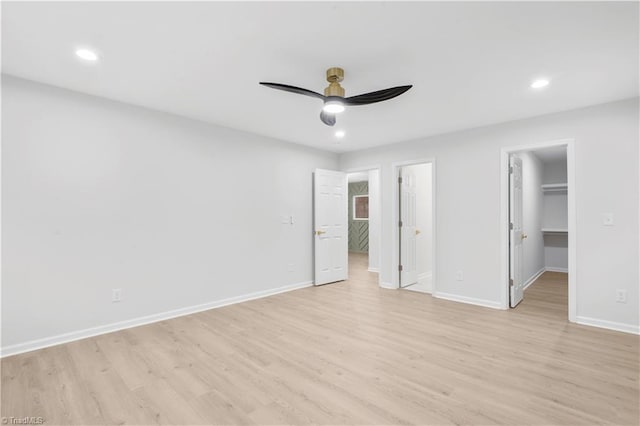 unfurnished bedroom featuring light wood finished floors, recessed lighting, a walk in closet, and baseboards