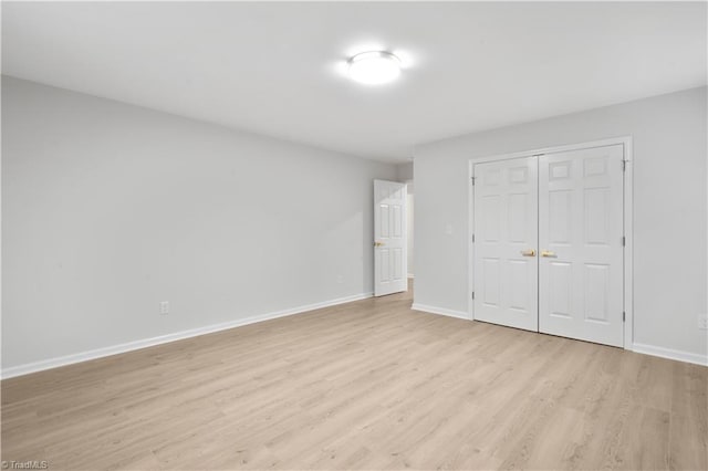 unfurnished bedroom featuring light wood-style floors, baseboards, and a closet