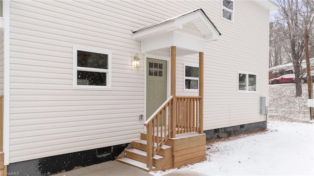 snow covered property entrance featuring crawl space