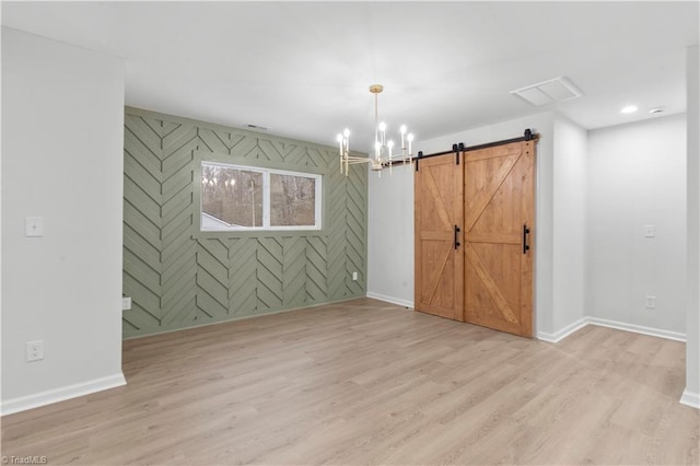 unfurnished room featuring light wood-style flooring, baseboards, and a barn door