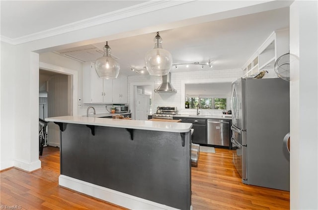 kitchen featuring a breakfast bar, white cabinets, decorative backsplash, hanging light fixtures, and stainless steel appliances