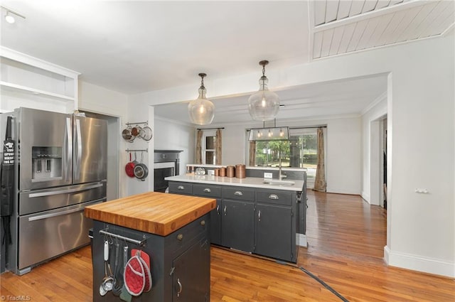 kitchen featuring sink, light hardwood / wood-style flooring, stainless steel fridge, a center island, and decorative light fixtures