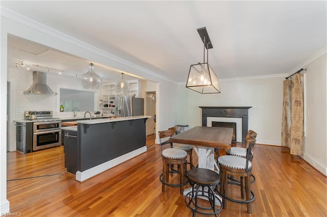 dining space with crown molding, sink, and light hardwood / wood-style flooring