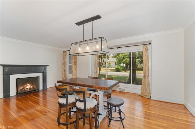 dining area with ornamental molding and light wood-type flooring