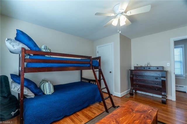 bedroom with hardwood / wood-style flooring, ceiling fan, and baseboard heating