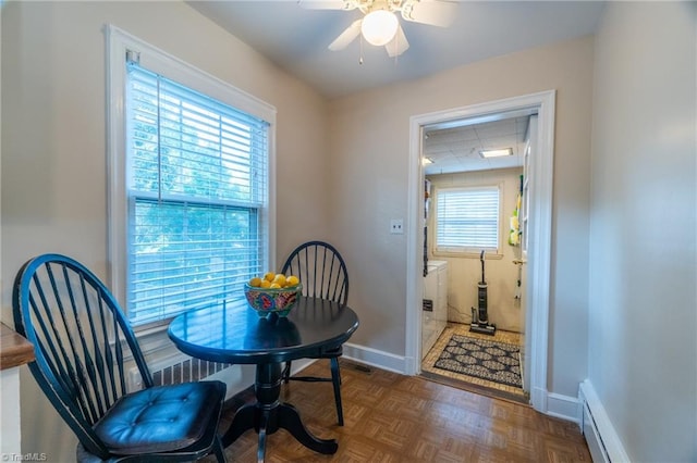 dining space with ceiling fan, dark parquet flooring, and a baseboard heating unit