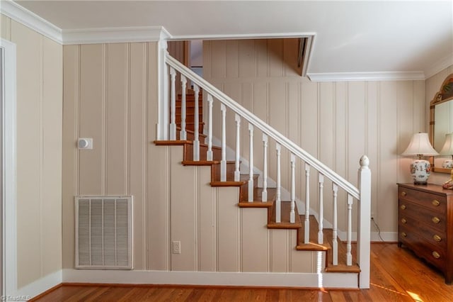 stairway with hardwood / wood-style flooring and crown molding