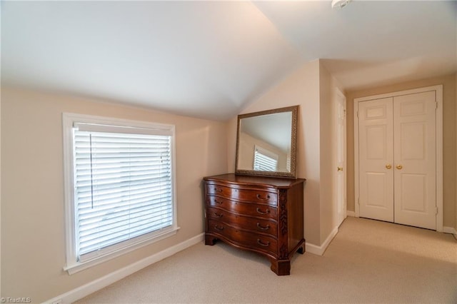 hallway featuring lofted ceiling and light carpet