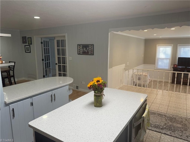 kitchen with a kitchen island, wood walls, and ornamental molding