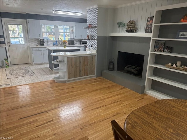 living room with light hardwood / wood-style floors, sink, crown molding, and a textured ceiling