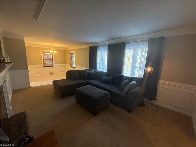 living room with ornamental molding, an inviting chandelier, and light carpet