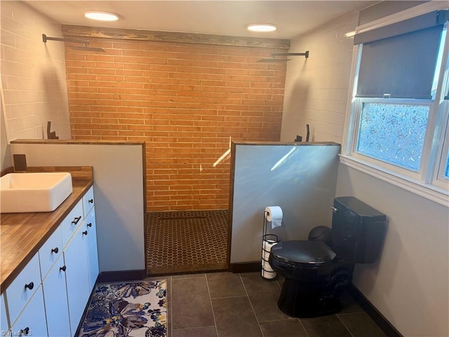 bathroom featuring a tile shower, toilet, vanity, and tile patterned floors