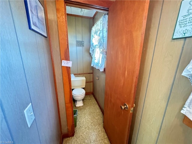 bathroom with toilet and wooden walls