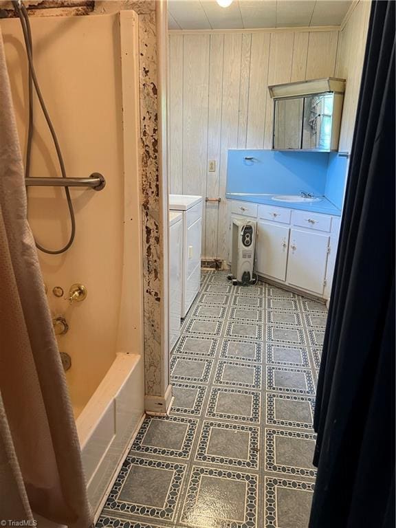 bathroom with washer and clothes dryer, vanity, wooden walls, and shower / bath combo