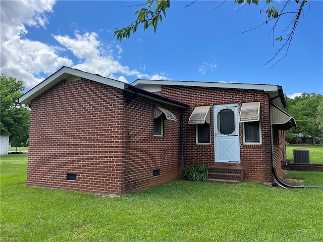 rear view of house featuring entry steps, central AC, a yard, and crawl space