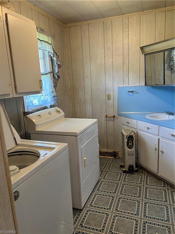 laundry room with cabinet space, separate washer and dryer, and wooden walls