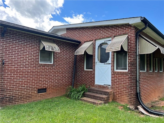 view of front of property with entry steps, brick siding, and crawl space