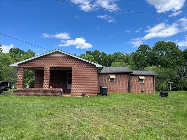 rear view of property featuring a yard, crawl space, and brick siding
