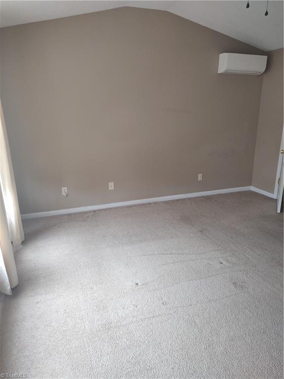 3855 Windstream Way, Jamestown, NC 27282 - carpeted spare room with a wall unit AC, lofted ceiling, and baseboards