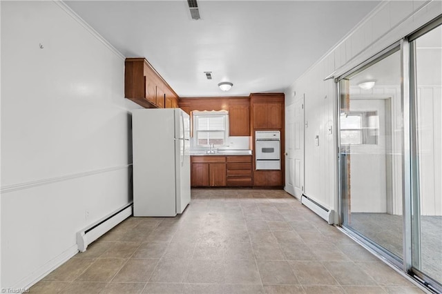 kitchen with brown cabinetry, white appliances, a baseboard radiator, and a warming drawer