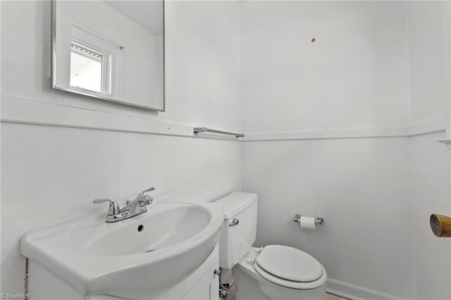 bathroom featuring toilet, vanity, and baseboards