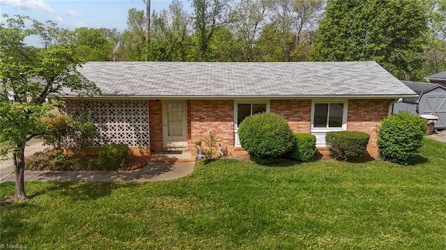 ranch-style home with brick siding, a shingled roof, and a front yard