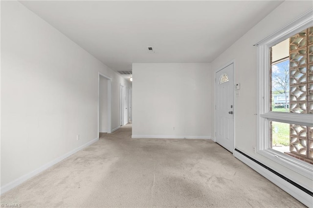 spare room featuring a baseboard radiator, a healthy amount of sunlight, baseboards, and light carpet