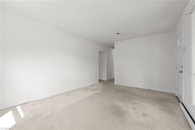 spare room featuring baseboard heating, baseboards, and light colored carpet