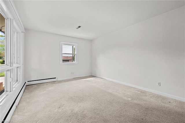 spare room featuring a baseboard heating unit, visible vents, baseboard heating, and light colored carpet