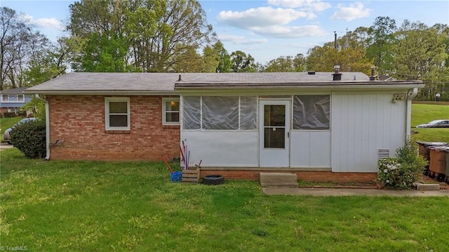 rear view of property featuring brick siding, a yard, and roof with shingles