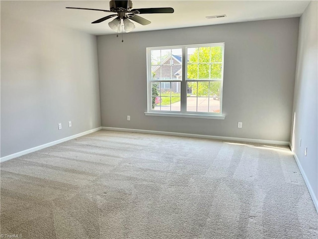 carpeted spare room with baseboards, ceiling fan, and visible vents