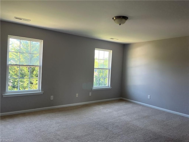 carpeted spare room featuring baseboards and visible vents