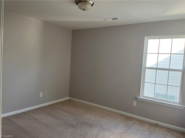 empty room featuring light colored carpet, baseboards, and visible vents