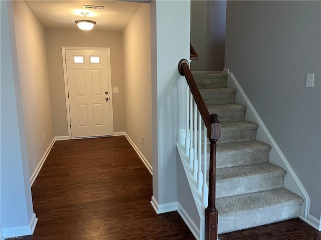 foyer with visible vents, baseboards, dark wood finished floors, and stairs