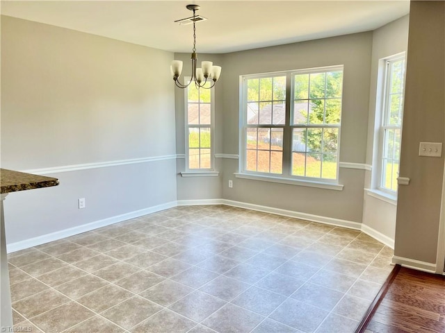 unfurnished dining area featuring baseboards, an inviting chandelier, plenty of natural light, and tile patterned flooring