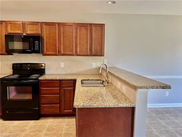kitchen with tasteful backsplash, a sink, light stone counters, black appliances, and a peninsula