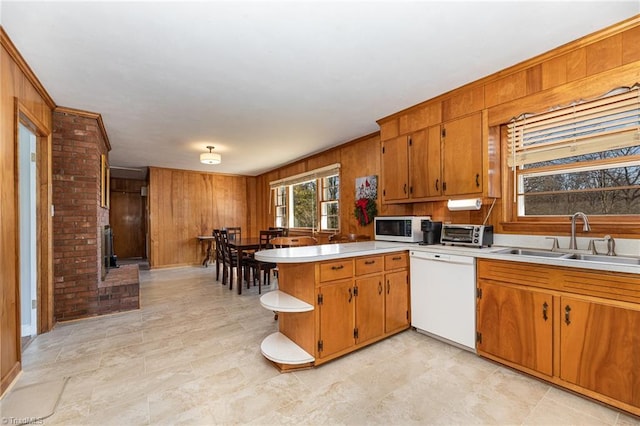 kitchen featuring sink, dishwasher, wood walls, and kitchen peninsula