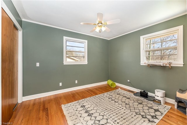 empty room with crown molding, ceiling fan, light hardwood / wood-style flooring, and a healthy amount of sunlight