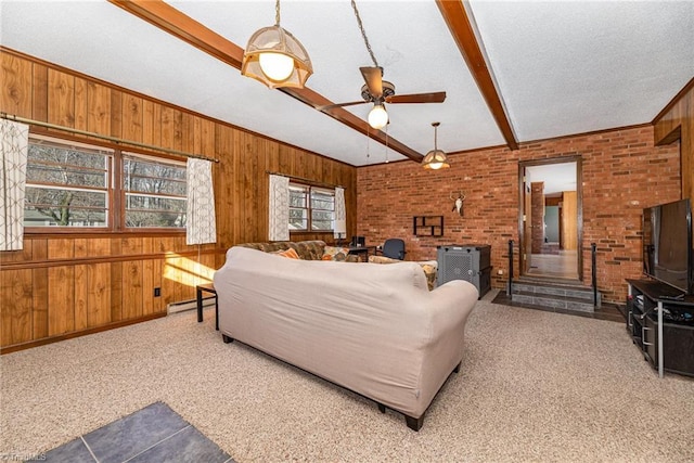 living room with carpet floors, brick wall, beam ceiling, and ceiling fan