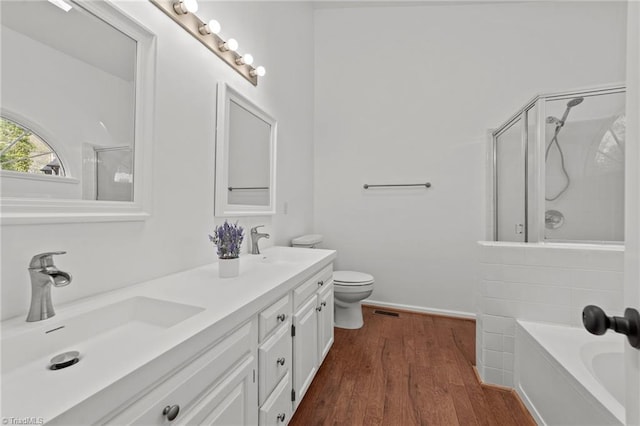 bathroom featuring wood finished floors, a shower with door, a sink, and a tub