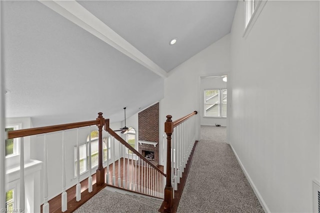 hall with lofted ceiling, carpet, visible vents, an upstairs landing, and baseboards