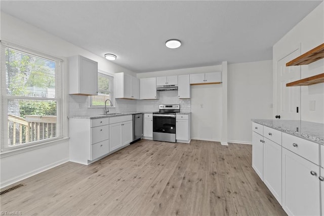 kitchen with open shelves, light wood-style floors, appliances with stainless steel finishes, under cabinet range hood, and visible vents