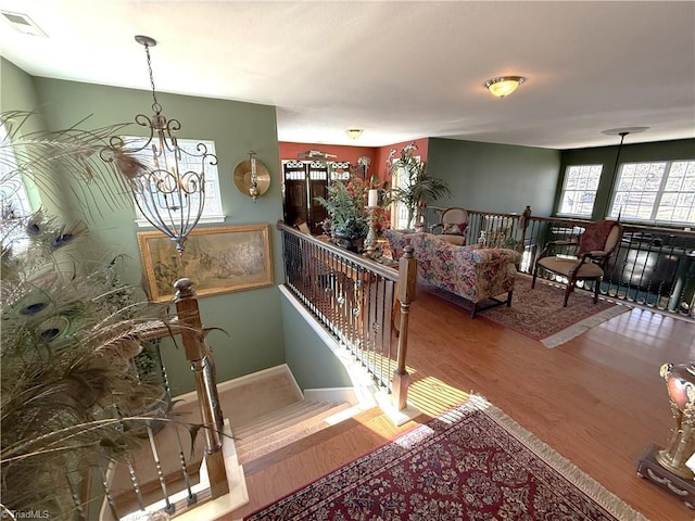 stairway with visible vents, baseboards, an inviting chandelier, and wood finished floors