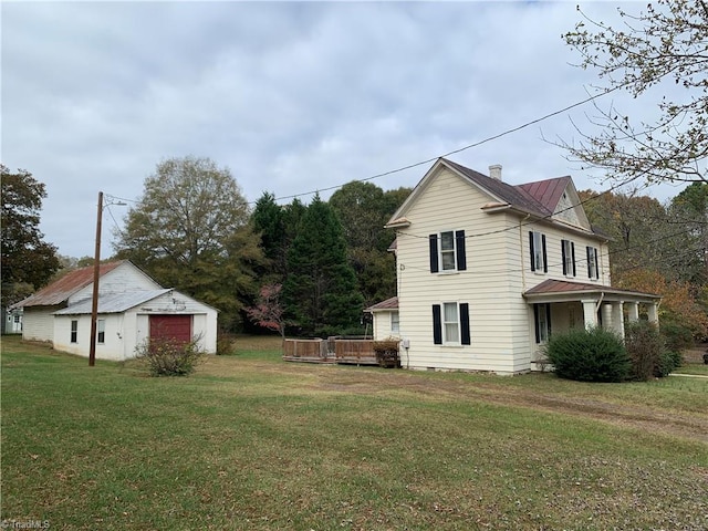 view of side of property with a garage, a lawn, and an outdoor structure