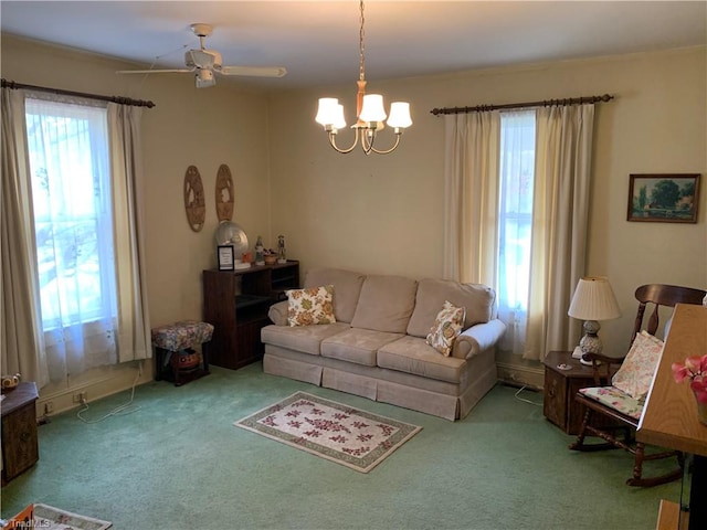 carpeted living room featuring ceiling fan with notable chandelier and plenty of natural light