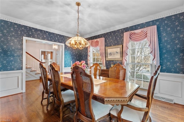 dining space with wood finished floors, visible vents, wainscoting, wallpapered walls, and an inviting chandelier