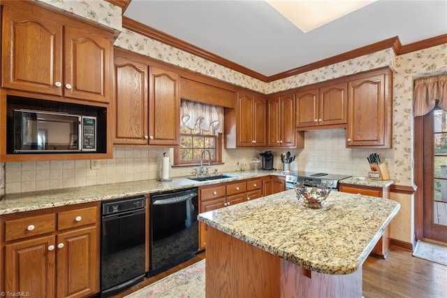 kitchen with light stone counters, wood finished floors, a sink, black appliances, and wallpapered walls